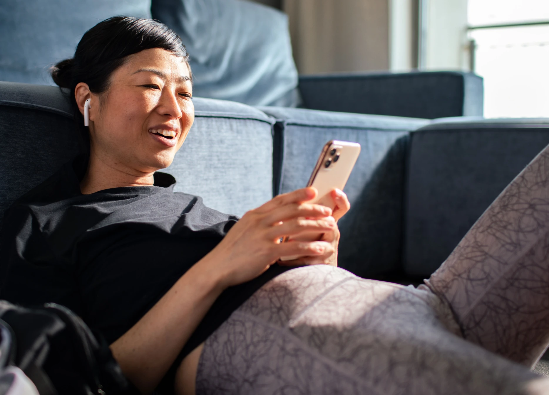 woman-with-airpods-on-couch-talking-to-her-phone